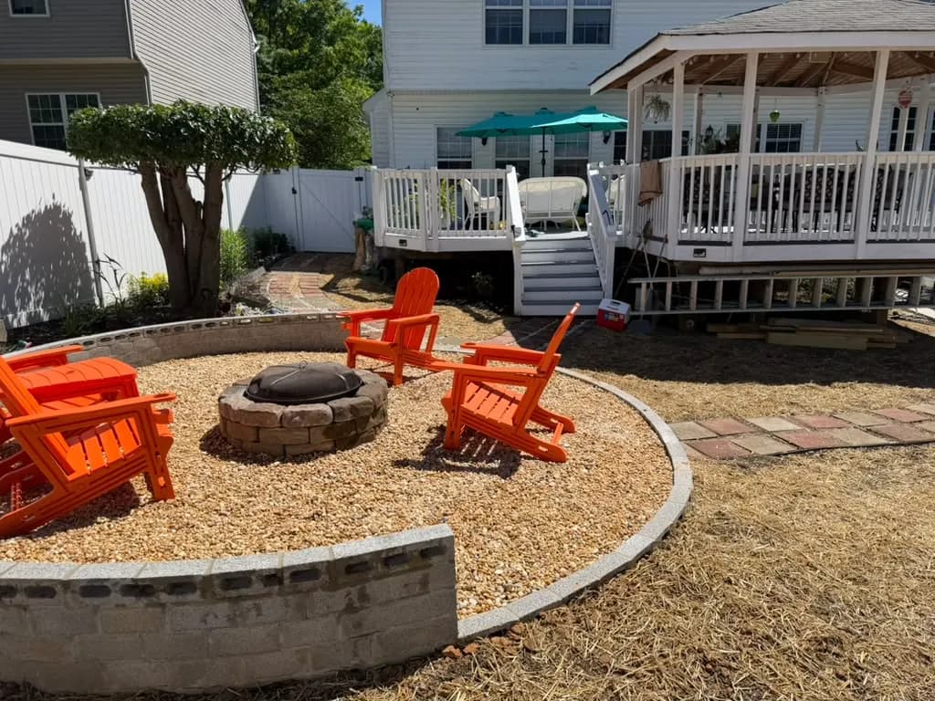 Circular gravel fire pit patio with a block seat wall built by Orbin